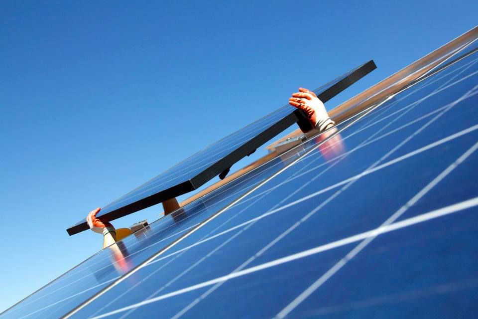 Solar panel being held up by installer.